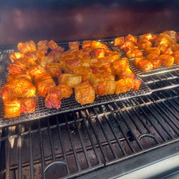Spiced pork belly burnt ends cooking on a grill at The Rusty Porthole.