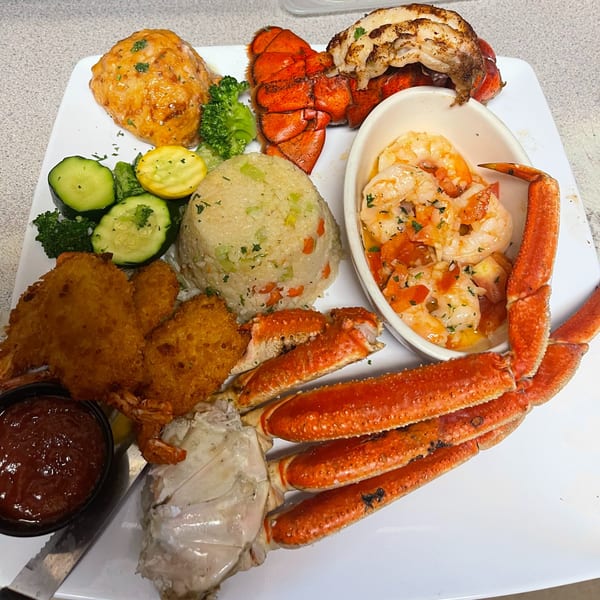 A seafood platter from The Rusty Porthole with lobster, crab legs, fried shrimp, and rice.